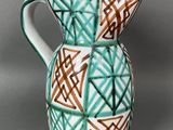 a green and brown vase with a geometric design on it
