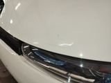 the front end of a white car with a denting dent