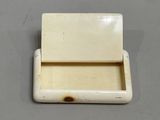 an ivory colored box with a lid on a gray surface