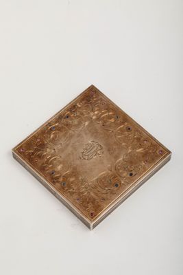 une vieille plaque en laiton ornée d'un motif sur un fond blanc