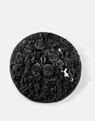 un chapeau noir orné de fleurs sur un fond blanc