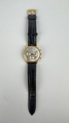 gros plan d'une montre sur une surface blanche avec un bracelet noir