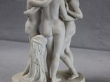 a statue of three women hugging each other on a table