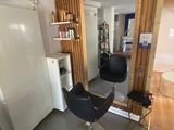 une photo d'un salon de coiffure avec un fauteuil et un réfrigérateur