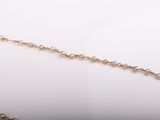 a close up of a gold chain with pearls on a white surface