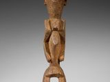 une image représentant une statue en bois d'un homme sur un socle
