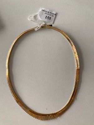 a gold necklace on a white table next to a pair of scissors