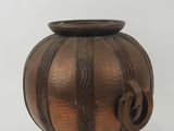 a brown vase with a flower on it on a white surface
