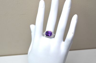 une image représentant la main d'un mannequin blanc portant une bague violette