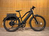 un vélo électrique noir garé devant un mur en bois