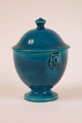 a small blue bowl with a lid on a white surface