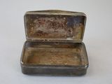 a small metal box with a lid on a white surface
