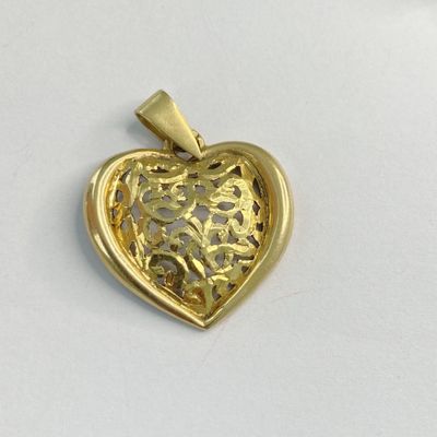 une image représentant un pendentif doré en forme de cœur posé sur une surface blanche