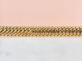 un gros plan d'un bracelet à chaîne dorée sur fond rose
