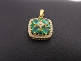 an emerald and diamond pendant on a black leather surface