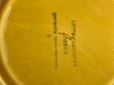a yellow vase with a label on it sitting on a table