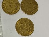 three gold coins sitting next to each other on a white surface