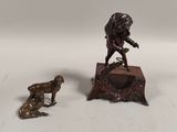 une statue en bronze représentant un homme et un chien, posée sur une table