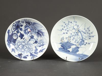 two blue and white plates with designs of birds and flowers on them