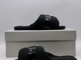 black sued slippers with buckles and a box on a white surface