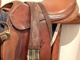 une selle de cheval et une selle posée sur un support en bois