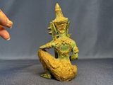 statue of a woman sitting on a rock with a hand on her hip