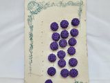 des boutons violets au crochet posés sur un morceau de papier bordé de vert