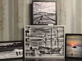 trois photos encadrées représentant un navire et un bateau, posées sur une table