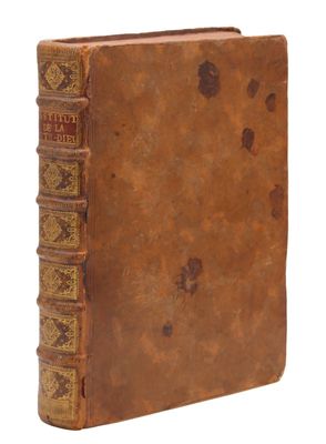 un vieux livre à la couverture brune posé sur une surface blanche