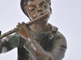 bronze statue of a boy playing a flute on a white background