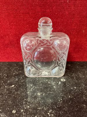 an empty glass bottle with a red lid sitting on a table