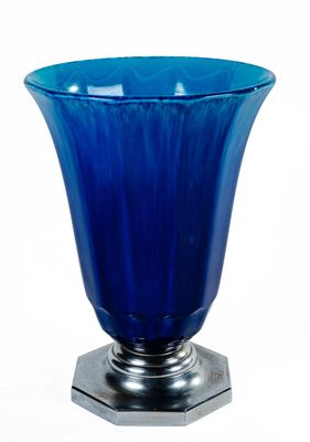 un vase en verre bleu posé sur un socle en métal