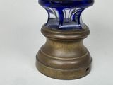 a blue glass vase with a gold base on a table