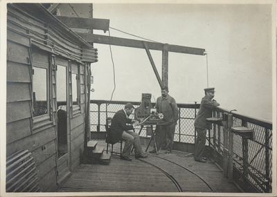 black and white photo of a group of men sitting on a deck
