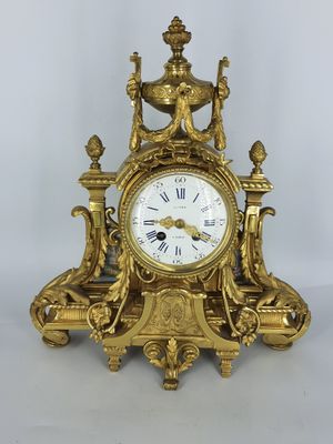 une horloge en or posée sur une table blanche