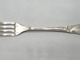 an old silverware fork with a flower on it on a table