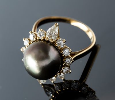 a close up of a black pearl and diamond ring on a black surface