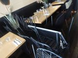 tables and chairs are lined up in a restaurant with a mirror on the wall