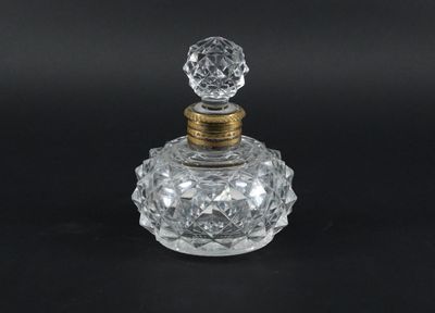 un flacon de parfum en verre transparent avec un bouchon doré, sur fond noir