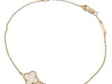 a gold bracelet with a white clover charm on a chain