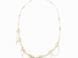 a gold necklace with leaves and beads on a white background