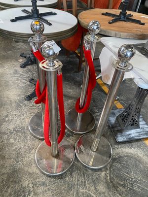 three silver pedestals with red rope on them in a room