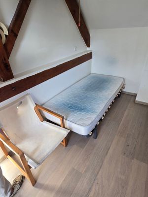une photo d'une chambre avec un lit et une chaise