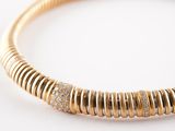 a close up of a gold bracelet with diamonds on a white surface