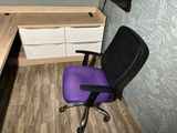 a purple office chair sitting in front of a computer desk