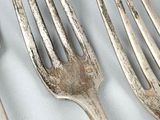 three forks and a spoon on a white table