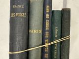 Plusieurs vieux livres sont alignés sur une étagère, attachés les uns aux autres