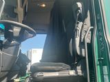 a green truck with its door open and the driver ' s seat down