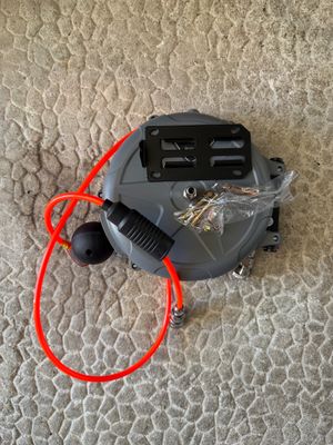 un aspirateur posé par terre, avec un cordon rouge