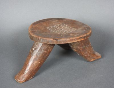 un vieux tabouret en bois posé sur une surface grise